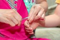 Mom cuts the child fingernails with small childrens scissors. Care and guardianship of children by parents