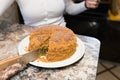 Mom cuts and serves a piece of freshly baked cake, which they have just made at home. The girl baked a cake and slices it Royalty Free Stock Photo