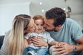 Mom, dad and baby kiss on sofa in living room of happy family home, young parents and child together. Love, happiness Royalty Free Stock Photo