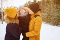 Mom and dad are cuddling and kissing their little son in winter park. Royalty Free Stock Photo