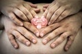 Mom and Dad hands holding pink pacifier, on Pregnant woman belly Royalty Free Stock Photo