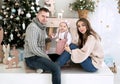 Mom and dad hold daughter`s hands on background of decorated Christmas tree Royalty Free Stock Photo