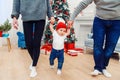 Mom and dad holding their cute baby and teaching him how to walk in the middle of the christmas decorated room. Royalty Free Stock Photo