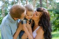 Mom and Dad hug and kiss their baby