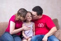 Mom and Dad kiss their daughter on couch