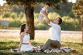 Mom, dad lifts high his baby boy up mid air and looks at her smiling. Happy parents spending time playing with son in park on Royalty Free Stock Photo