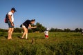 Mom, dad and little son watch and photograph a wild ground squirrel in a meadow with people resting on a sunny summer day