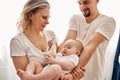 Mom and dad are playing with their little child in a bright room, all dressed in white t-shirts. Loving parents spend Royalty Free Stock Photo