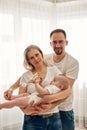 Mom and dad are playing with their little child in a bright room, all dressed in white t-shirts. Loving parents spend Royalty Free Stock Photo