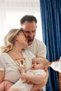 Mom and dad are playing with their little child in a bright room, all dressed in white t-shirts. Loving parents spend Royalty Free Stock Photo