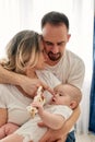 Mom and dad are playing with their little child in a bright room, all dressed in white t-shirts. Loving parents spend Royalty Free Stock Photo