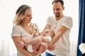 Mom and dad are playing with their little child in a bright room, all dressed in white t-shirts. Loving parents spend Royalty Free Stock Photo