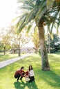 Mom and dad squatted near a little girl on a green grass