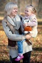 Mom and daughter child with ponytails with soft toy hedgehog smiling in sunny autumn park outdoors Royalty Free Stock Photo