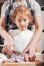 Mom and daughter cut onions together. Mom teaches daughter to cook. Lifestyle. Vertical shot Royalty Free Stock Photo