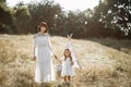 Mom and daughter, dressed in indian boho style with feather in hair, posing in wild meadow Royalty Free Stock Photo