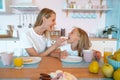 Mom and daughter are fooling around in the kitchen with donuts. cute family photo. dressed in white tshirts