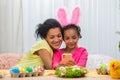 Mom and daughter with funny bunny ears take selfies and have fun. African American woman and little girl are sitting at