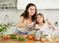 Mom and daughter taste soup in kitchen, take out portion of food from pan. Royalty Free Stock Photo