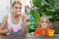 Mom and daughter having breakfast with tea and sandwiches sitting on the veranda