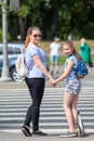 Mom and daughter holding hands on pedestrian crossing, waiting green light. Looking at camera Royalty Free Stock Photo