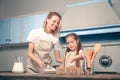 Mom and daughter in the kitchen cook Mafins. A daughter holds a chicken egg in her hand which will add to the flour Royalty Free Stock Photo