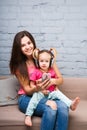 Mom and daughter listen to music in big headphones put on their head, sitting on the sofa. Holds the phone.