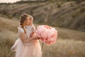 Mom with daughter in pink fairy-tale dresses walk in nature. The childhood of the little princess. Large pink decorative flowers