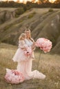 Mom with daughter in pink fairy-tale dresses walk in nature. The childhood of the little princess. Large pink decorative flowers