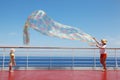 Mom and daughter play with chiffon scarf on deck