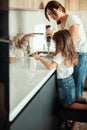 Mom and daughter prepare icing for gingerbread in their home kitchen. Beat with a blender. The girl helps the woman. Royalty Free Stock Photo