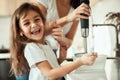 Mom and daughter prepare icing for gingerbread in their home kitchen. Beat with a blender. The girl helps the woman. Royalty Free Stock Photo