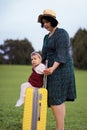 Mom and daughter are preparing for the trip. A little girl sits on a yellow suitcase suitcase. Go on a trip, relax at sea, collect Royalty Free Stock Photo