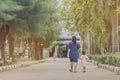 Mom and daughter pupil girl holding hand in hand on street go to the classroom