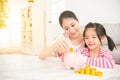 Mom and daughter putting coins into piggy bank Royalty Free Stock Photo