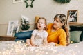 Mom and daughter are reading a book and smiling, sitting at home on the bed. New Year, Christmas, family, time together Royalty Free Stock Photo