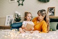 Mom and daughter are reading a book and smiling, sitting at home on the bed. New Year, Christmas, family, time together Royalty Free Stock Photo