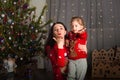 Mom and daughter in a red sweater for Christmas at the Christmas tree. A girl and her mother are hugging, kissing at the Christmas Royalty Free Stock Photo