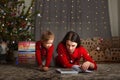 Mom and daughter in a red sweater for Christmas at the Christmas tree. The girl and her mother read books, fairy tales at the Chri Royalty Free Stock Photo