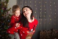Mom and daughter in a red sweater for Christmas at the Christmas tree. A girl and her mother are hugging, kissing at the Christmas Royalty Free Stock Photo