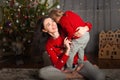 Mom and daughter in a red sweater for Christmas at the Christmas tree. A girl and her mother are hugging, kissing at the Christmas Royalty Free Stock Photo