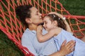 Mom and daughter resting in a hammock in nature on a warm sunny summer day. Happy family spending time in countryside Royalty Free Stock Photo