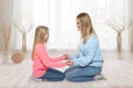 Mom and daughter sit on the floor holding each other`s hands with love  at home Royalty Free Stock Photo