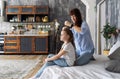 Mom and daughter are sitting on the bed and mom gently braid pigtails. European interior.