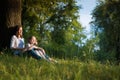 Mom and daughter are sitting near a tree Royalty Free Stock Photo