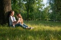 Mom and daughter are sitting near a tree Royalty Free Stock Photo