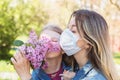 Mom and daughter sniffing a lilac on the street. Quarantine quit concept