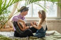 mom and daughter on the sofa, playing the guitar. a woman and a girl compose music, songs togethe Royalty Free Stock Photo