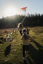 Mom with daughter and son and white half-breed dog. Happy family runs around field at sunset and plays with kite. Launch Royalty Free Stock Photo