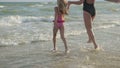 Mom and daughter flee along the beach to swim in the sea